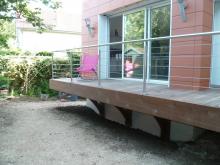 Balcon en bois et doublage extérieur en plaques en terre cuite fixées sur des rails métal.