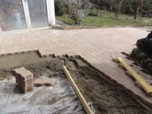 Pose de pavés autobloquants, dans une allée, sur une chape en béton pour une meilleure durabilité. (Pendant)